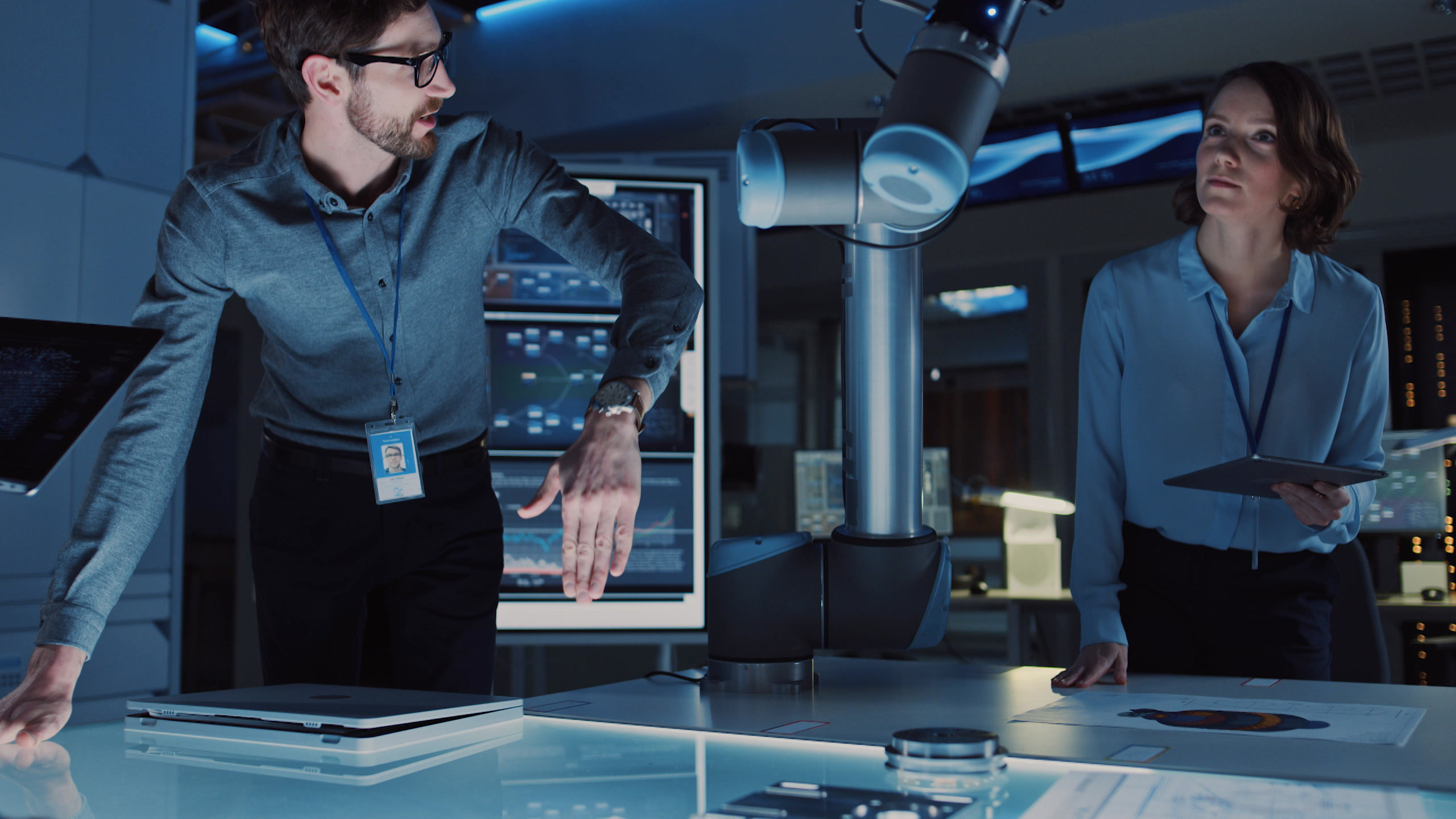 Two engineers at a workstation reviewing a collaborative robot arm